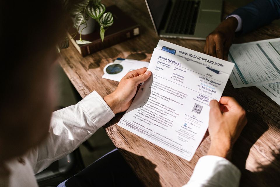 A person's hands holding a printed notice over papers on a wooden desk