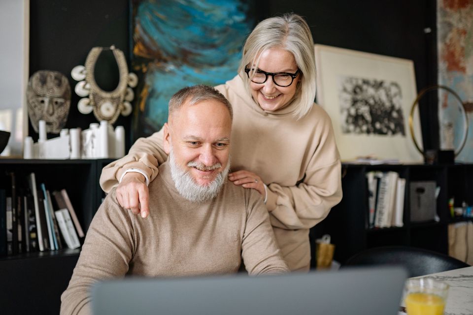 A smiling older couple looking at a laptop together at home