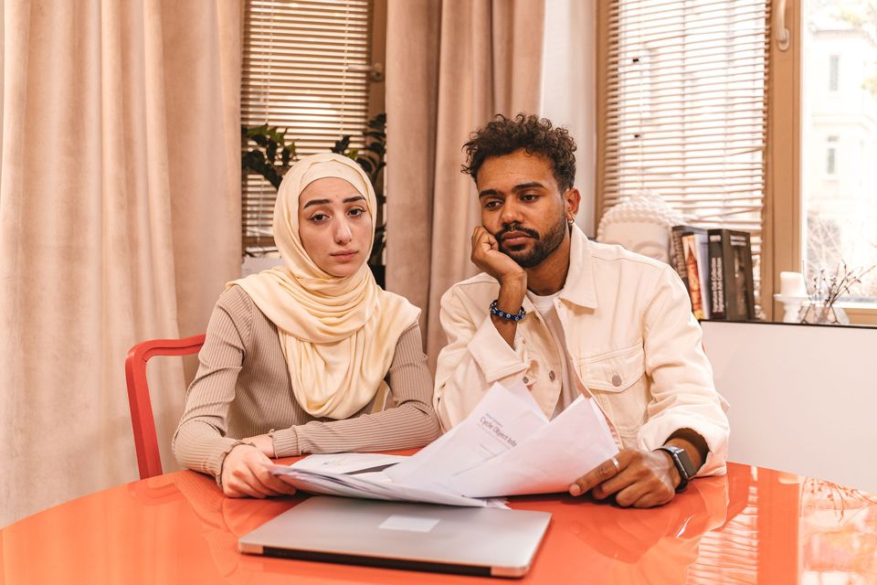 A couple looking worried over documents and a laptop at a table
