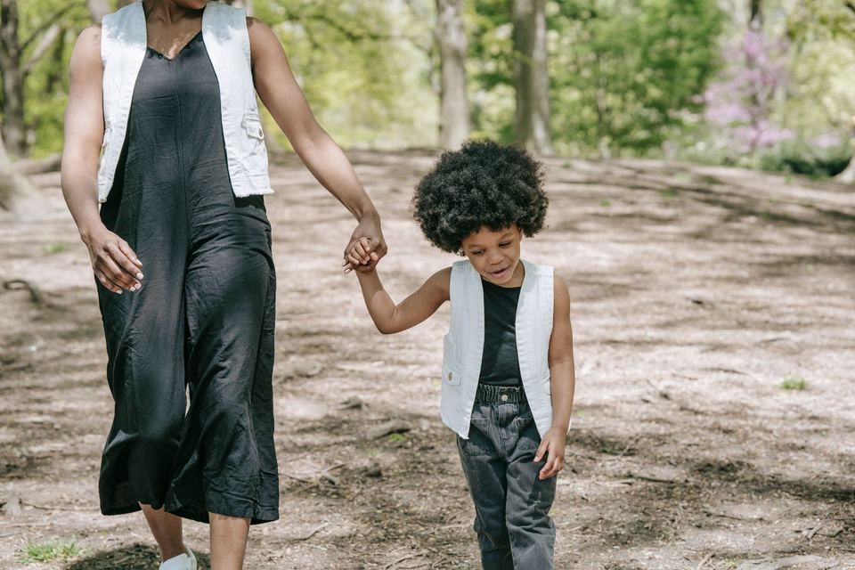 An adult and a young child walking hand in hand on a path