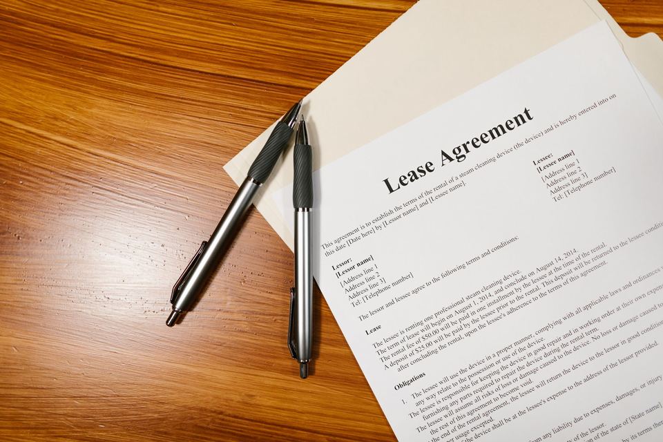 A lease agreement on a wooden table with two pens