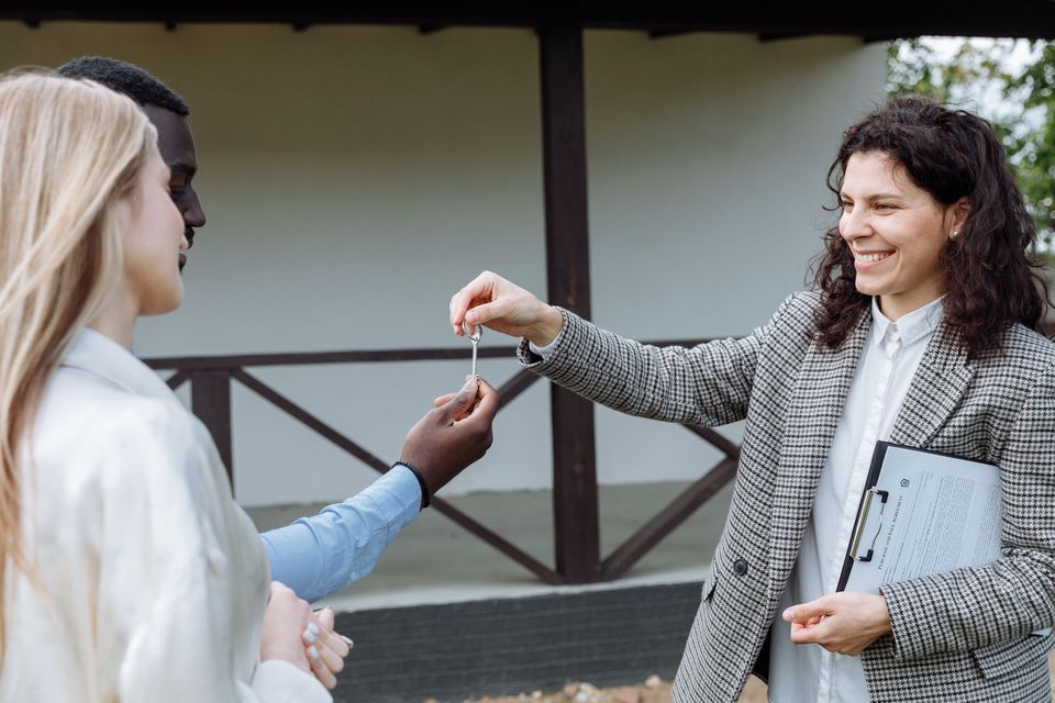 A real estate agent handing house keys to a smiling woman