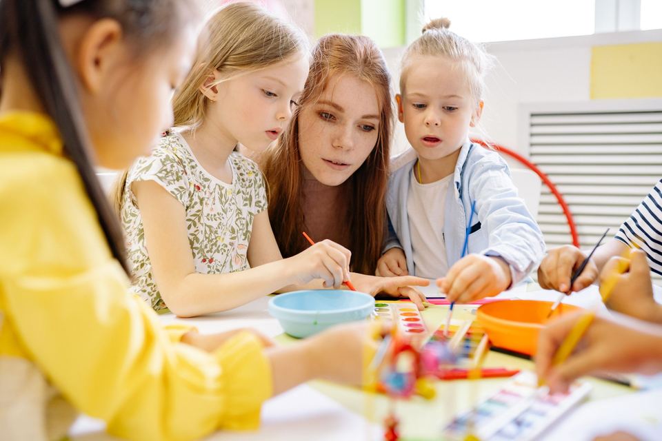 A teacher and three young girls doing a craft activity together