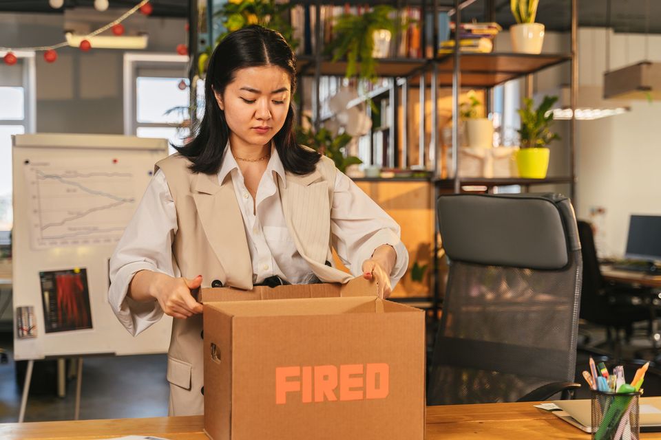 A woman in an office putting belongings into a cardboard box
