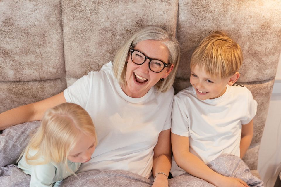 A grandmother laughing with two grandchildren on a couch