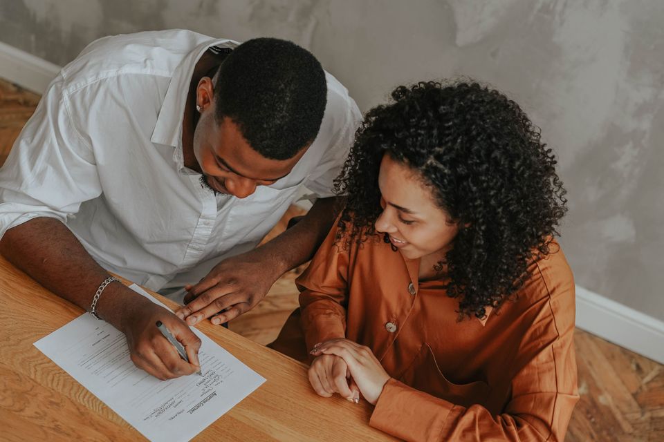 A smiling couple filling out a form together at a table