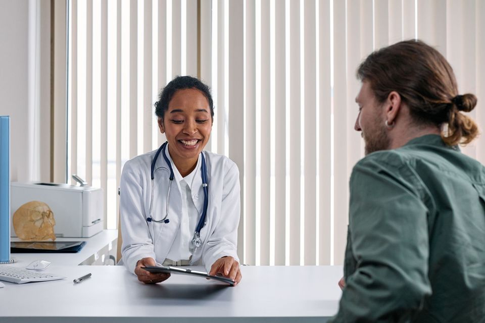 A smiling doctor reviewing a chart with a patient across a desk