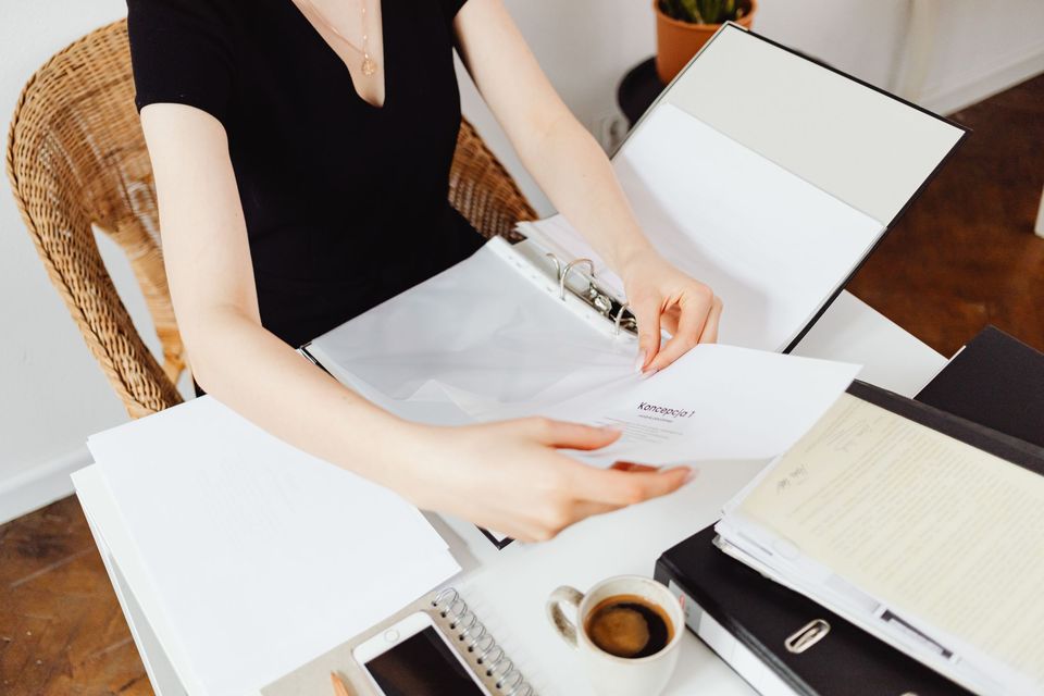A woman placing documents into a binder at a desk