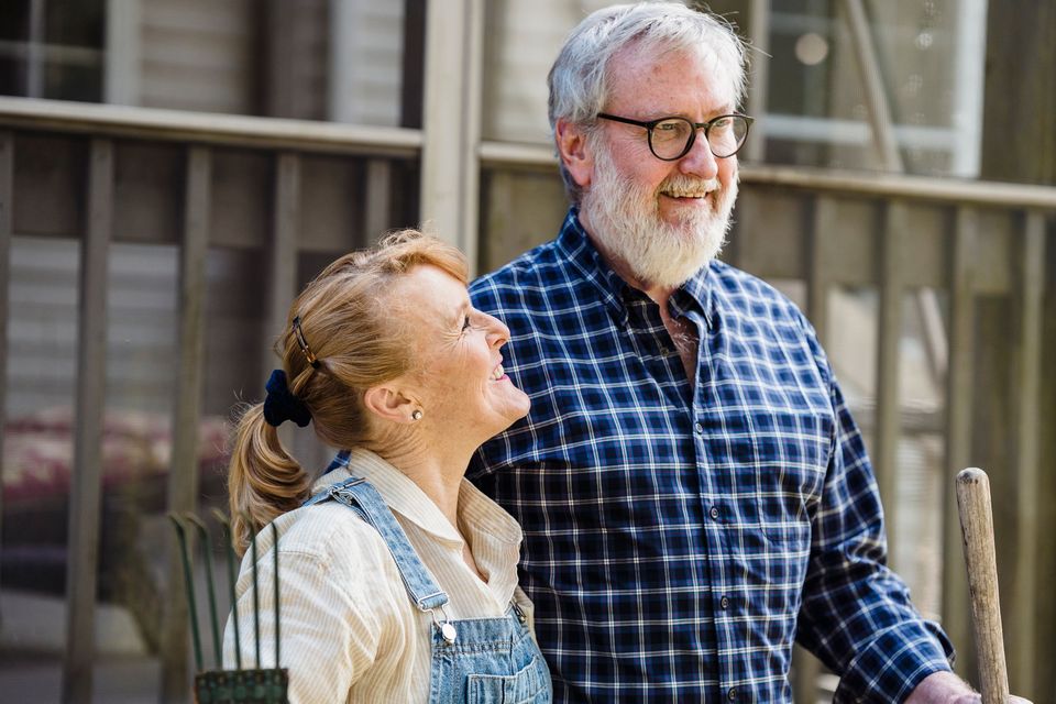 An older man and a woman smiling at each other on a porch
