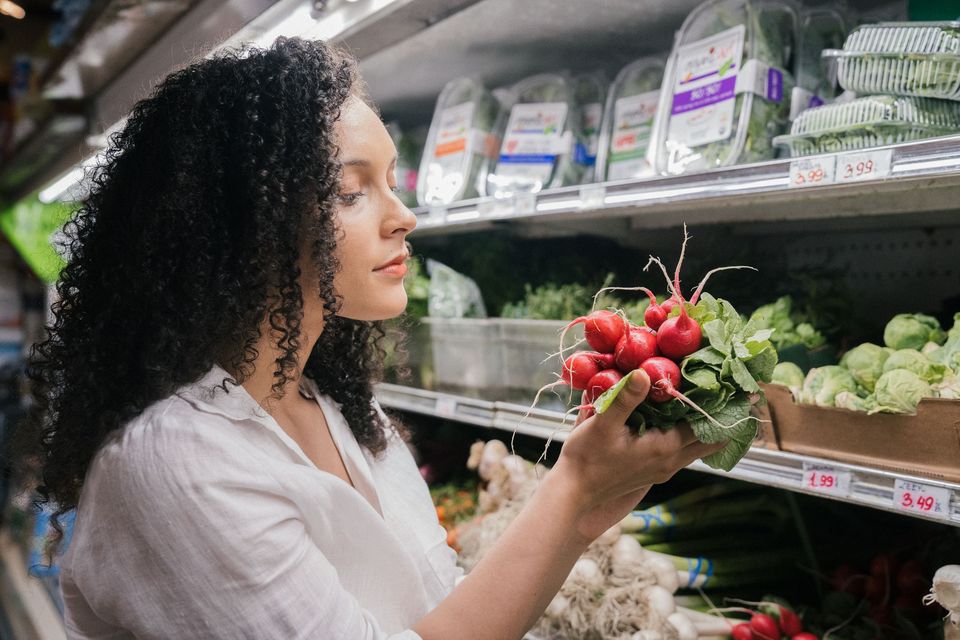 A woman choosing fresh radishes in a grocery store