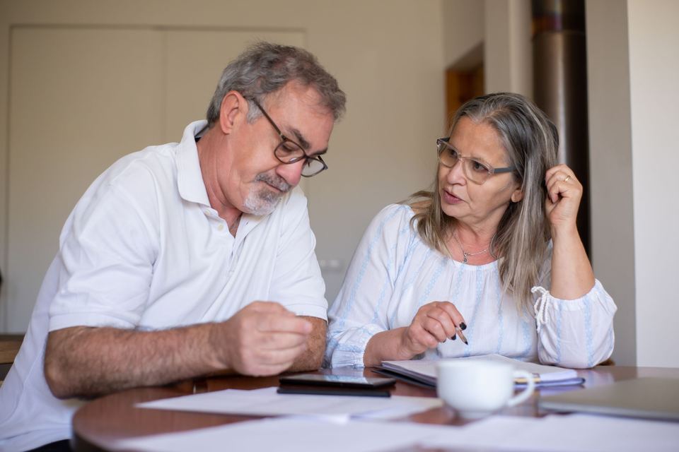 An older couple sitting at a table going over papers together