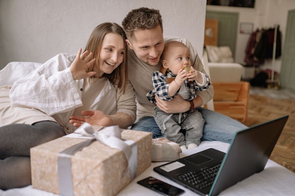 A couple sitting with their baby beside an open laptop at home