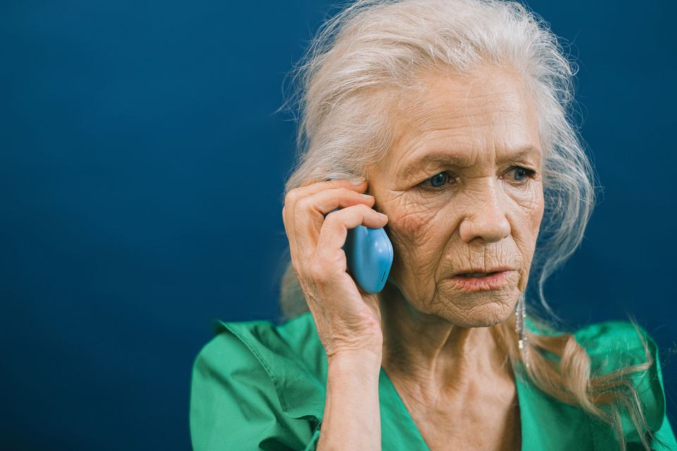 An older woman on a phone call with a worried expression
