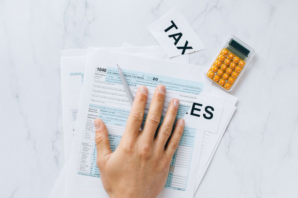 A hand resting on a tax form beside a small calculator