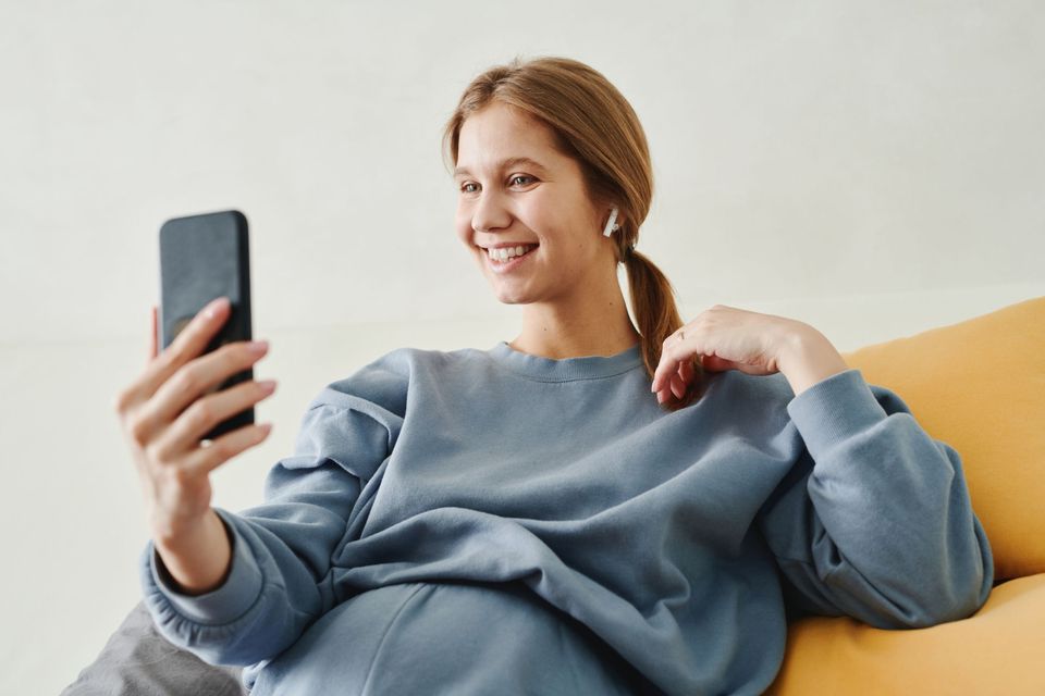A smiling woman looking at her phone on a couch