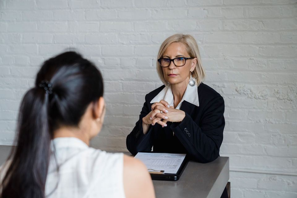 Two women talking across a small table during a counseling meeting