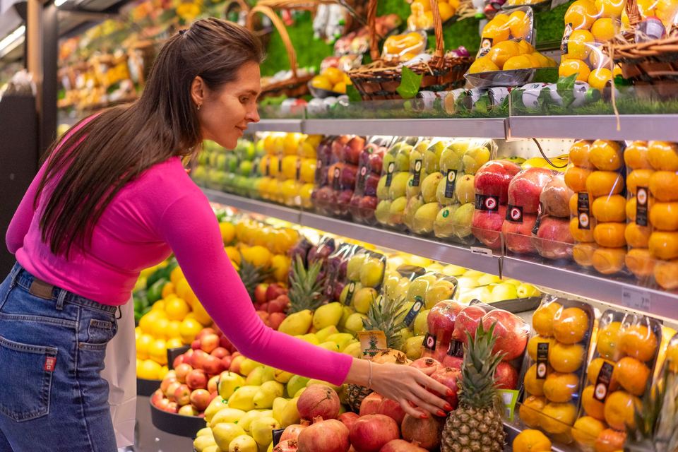 A woman choosing fruit at a grocery store display