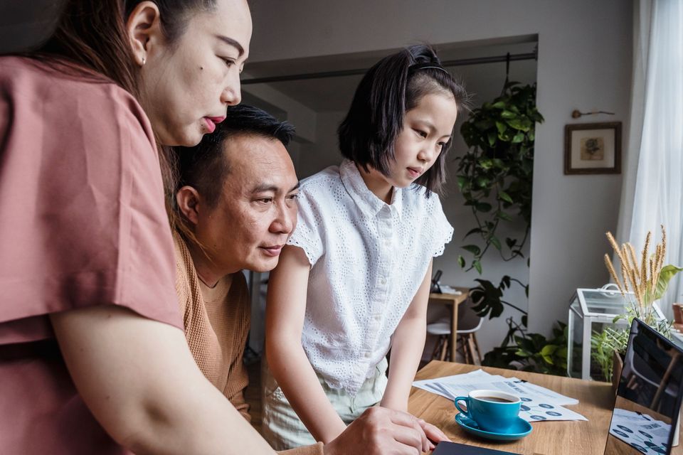 A father, mother and daughter looking over papers together at a table