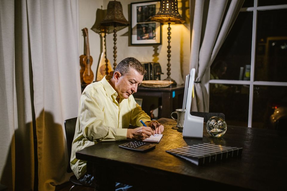 An older man working at a desk with a calculator and papers